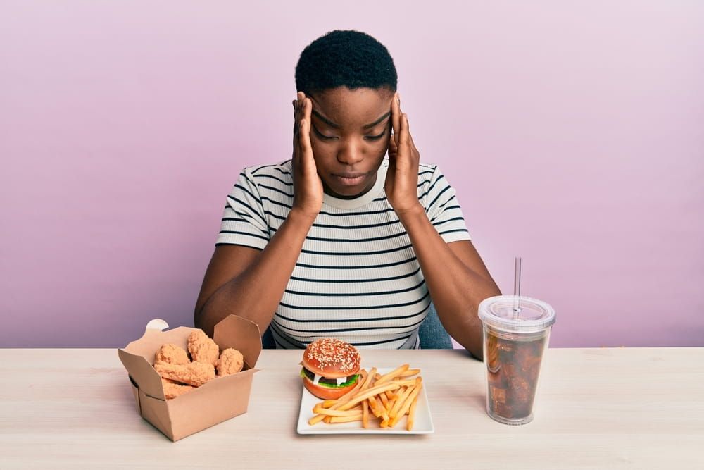Young african american woman eating a tasty classic burger with fries and soda