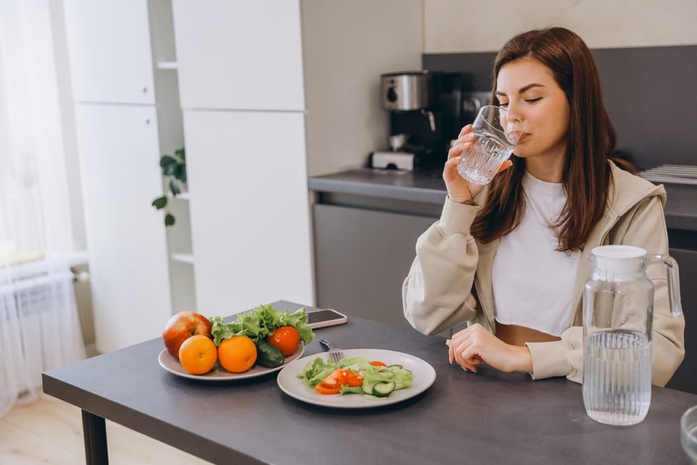 Young woman enjoying a healthy meal with fresh salad and drinking water