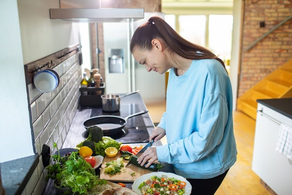 Young adult woman preparing a healthy salad in the kitchen