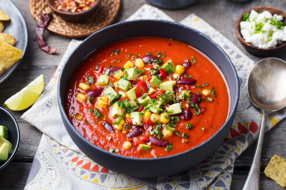 Mexican tomato, bean, bell pepper soup in black bowl.