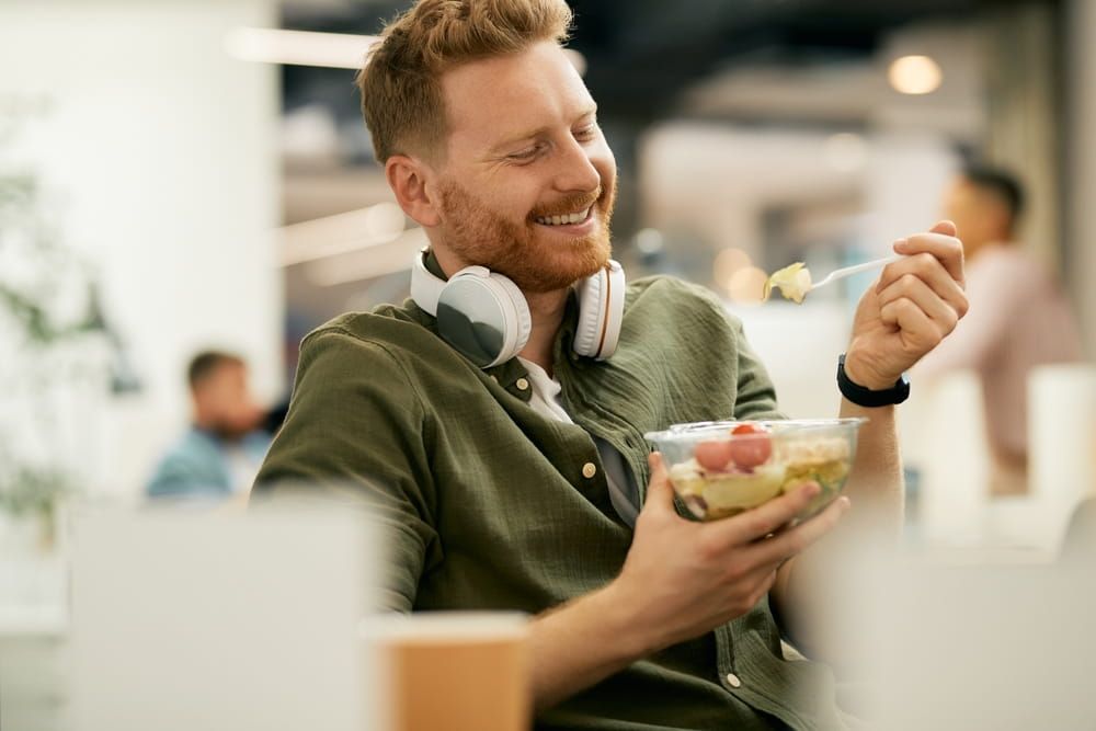 Happy businessman having a healthy meal during lunch break at work.