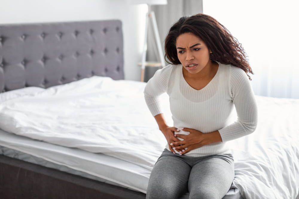 upset black woman suffering from strong abdominal pain in right side