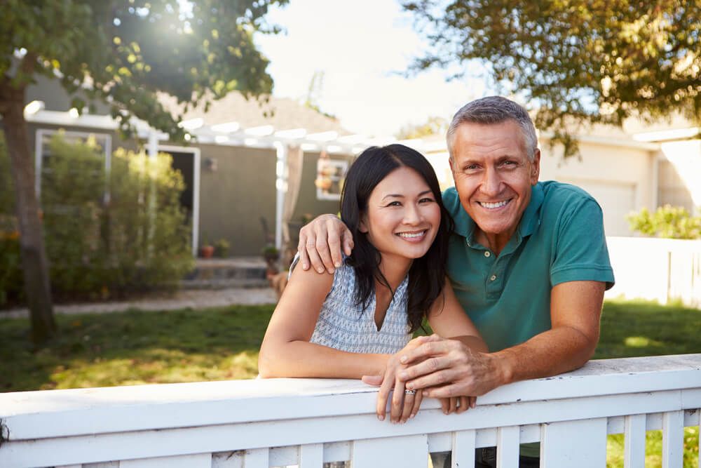 Happy couple Looking Over Back Yard Fence