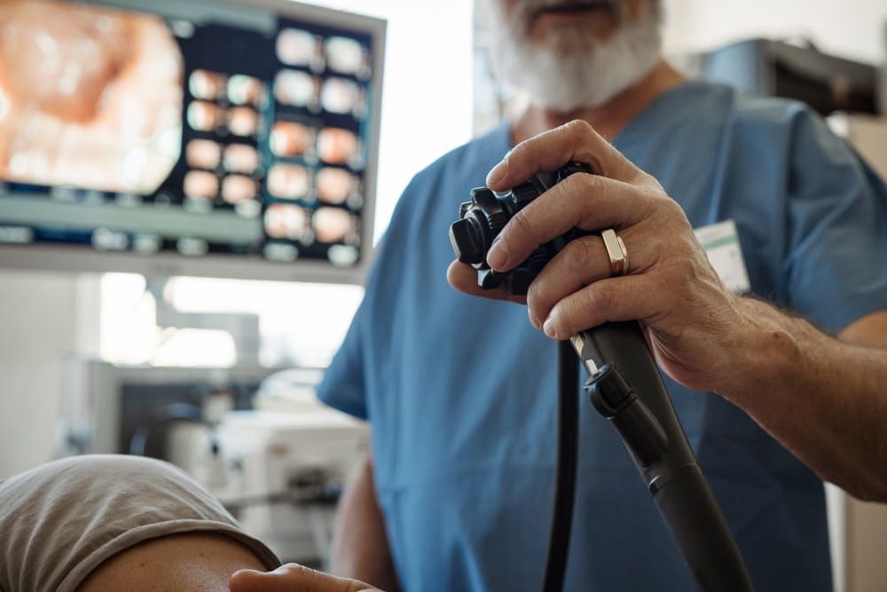 Doctor looking at monitior during gastroscopy procedure, examining upper digestive tract.