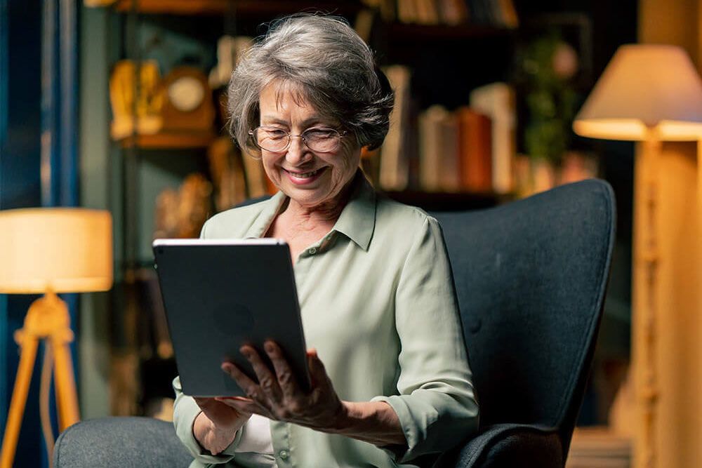 elderly woman sitting watching a news from tablet