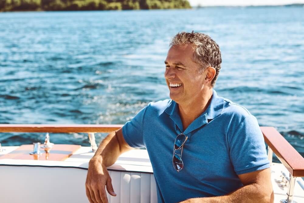 Mature man, boat and travel with thinking for retirement, smile on water cruise for future plan