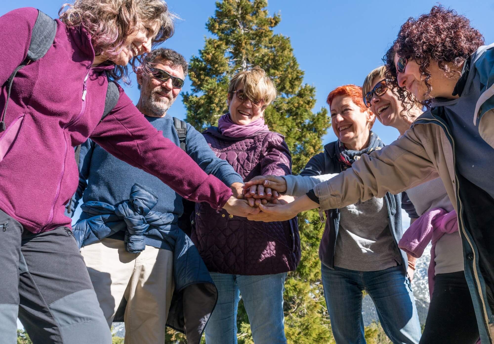 A bunch of friends in their 50's practice mountain hiking at spring time