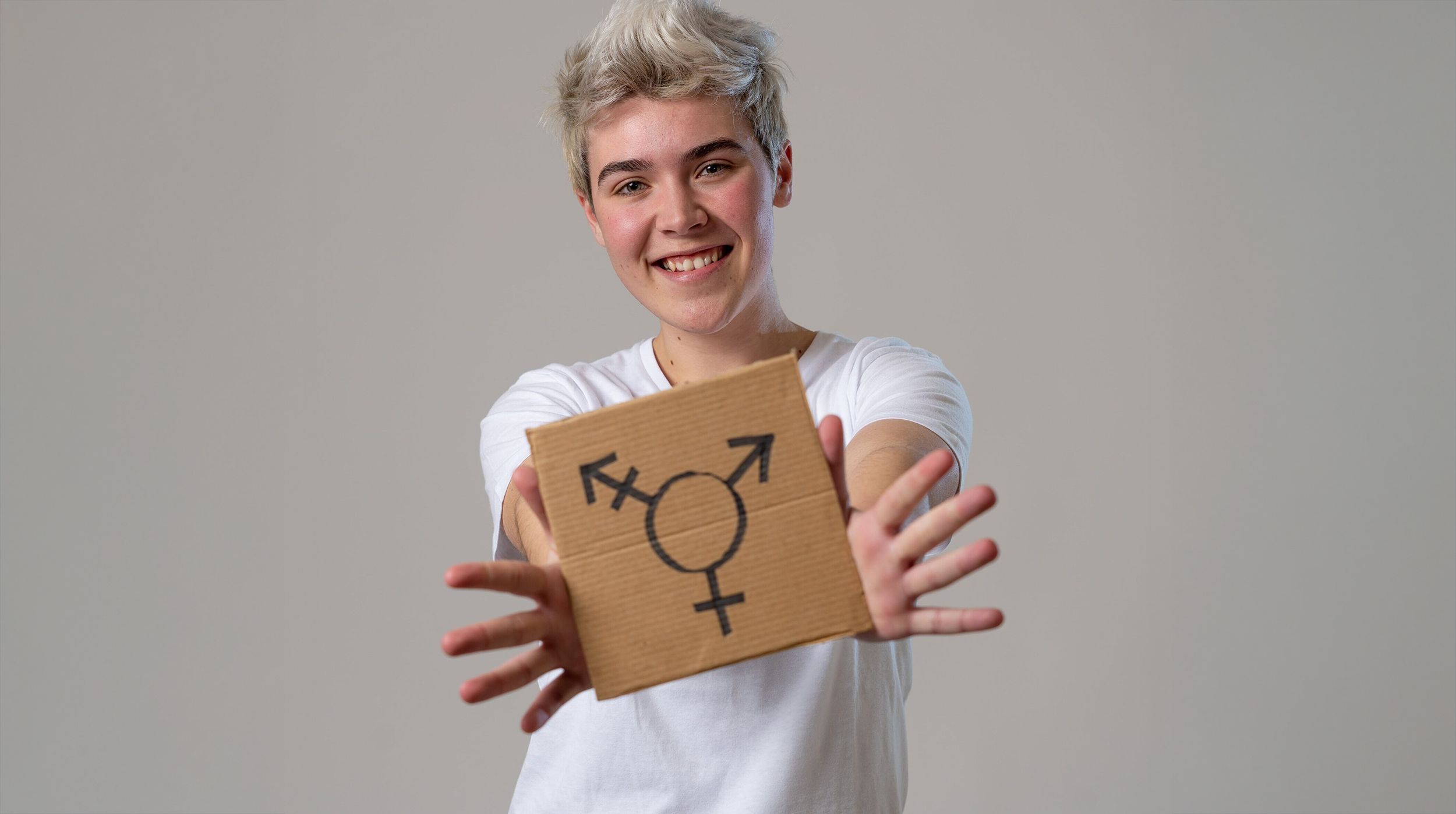 Inclusive aesthetic medicine imagery featuring a smiling person holding a nonbinary gender symbol sign, representing gender-affirming care, self-expression, and LGBTQ+ inclusivity.