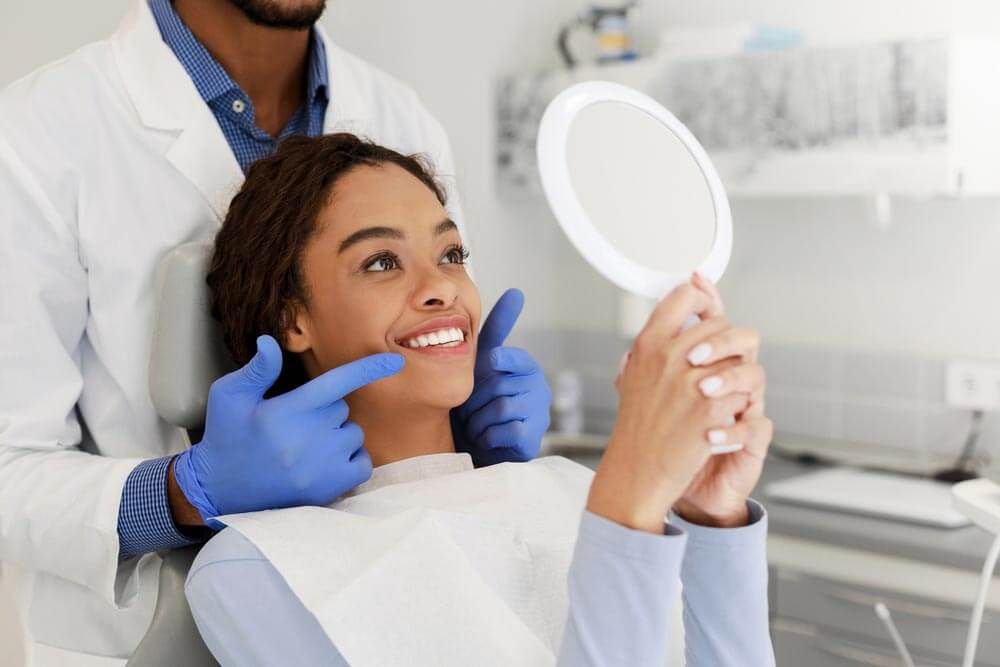 a patient reviewing their new smile in a mirror while at a dental checkup