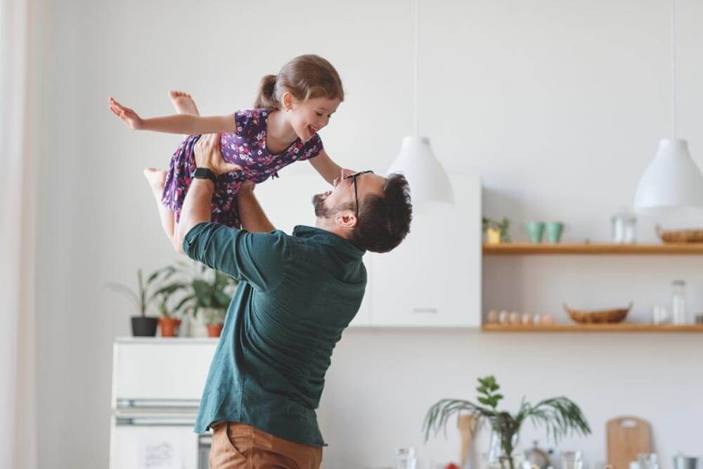 a man holding up a young child in a kitchen