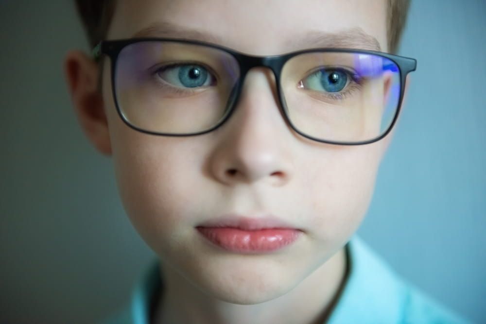 close up part child face, boy 10 years old wearing glasses, human eye looking to side, vision examination, diagnosis, treatment ophthalmic diseases, emotional development children