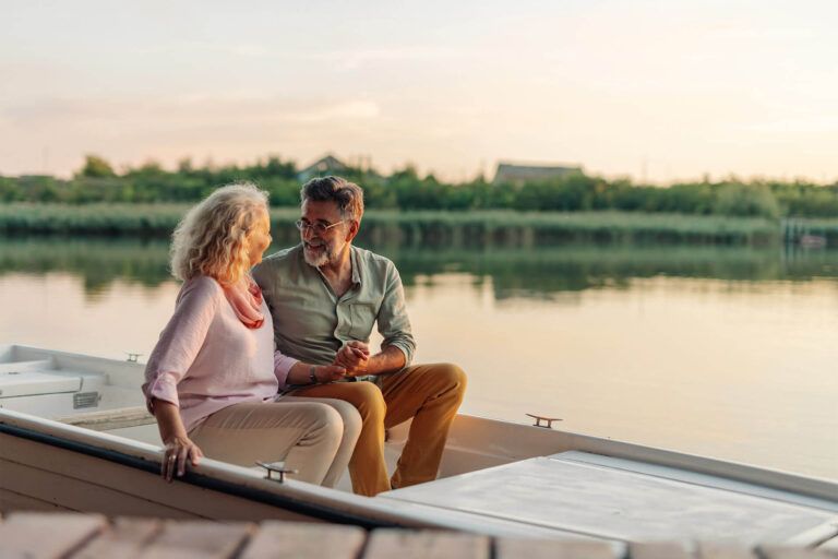 Happy senior couple holding hands and enjoying a romantic moment together while sitting in a boat on a calm lake