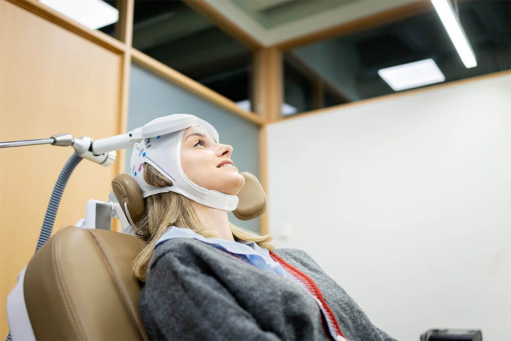 A Caucasian girl between 20 and 30 years old undergoes transcranial magnetic stimulation therapy