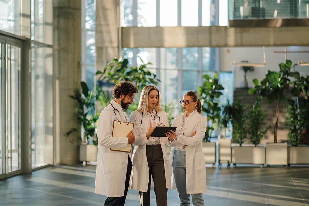 Doctors collaborating in a modern hospital lobby, using a tablet and clipboard to enhance patient care and streamline communication