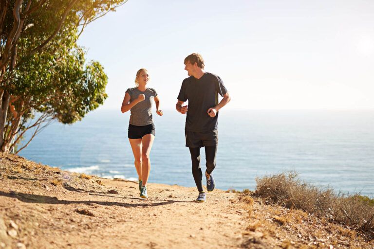 Running, nature and couple with fitness, smile and bonding together with happiness, holiday and cardio