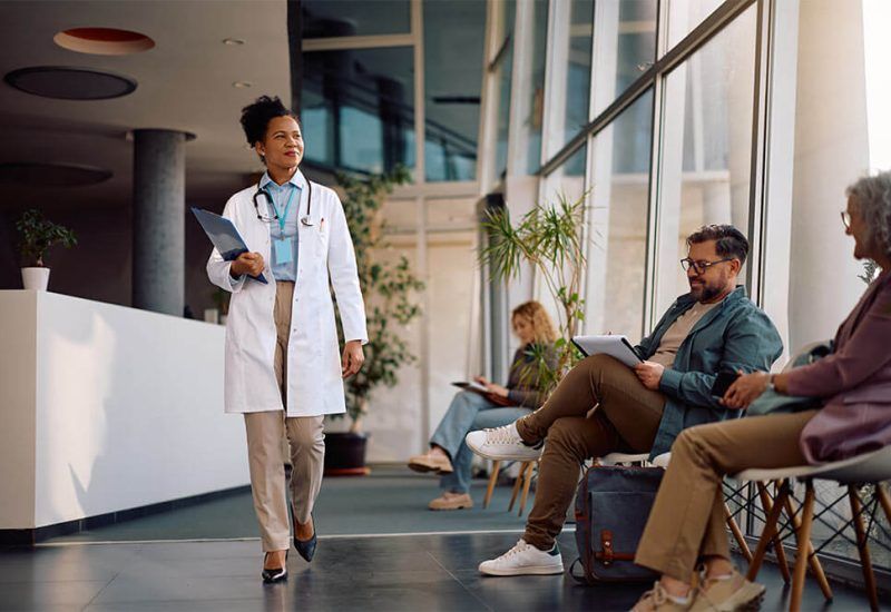 African American female doctor walking through waiting room while working at the clinic.