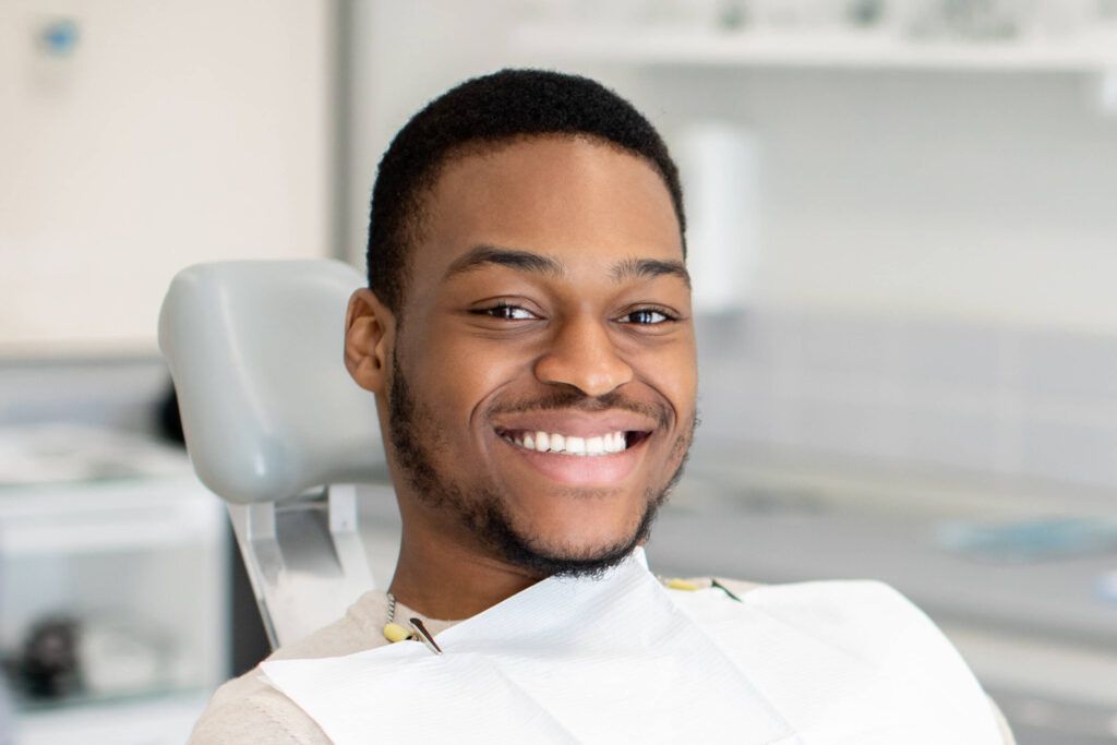 a patient smiling while sitting in a dental chair during an appointment.