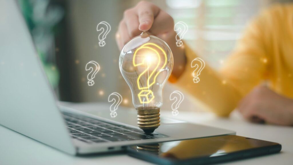 Hand touching the light bulb with the question mark inside