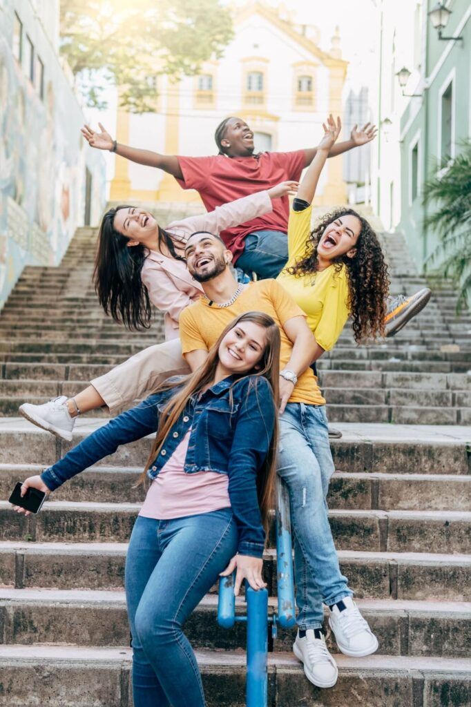 Group of happy young brazilian friends having fun sitting on the handrail of a stairs in the city center