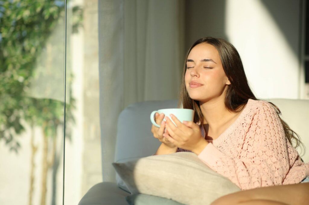 Woman relaxing at home drinking tea sitting on a couch at home