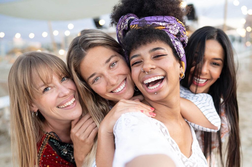 group of happy friends taking a selfie together on a beach