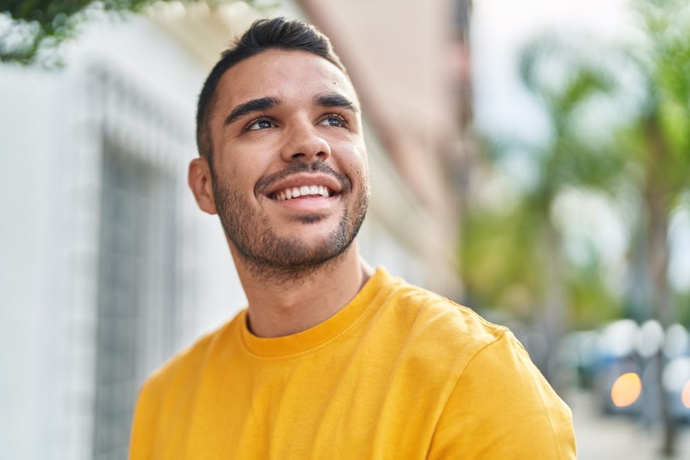 Young Hispanic man smiling confident looking to the sky at street