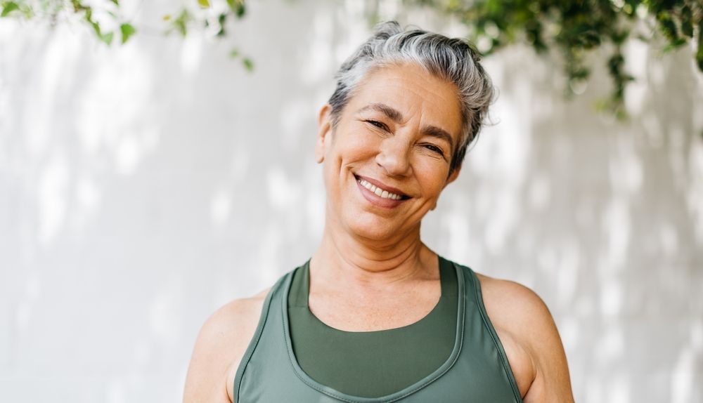 Mature woman looking at the camera with a happy smile as she takes on her outdoor workout routine