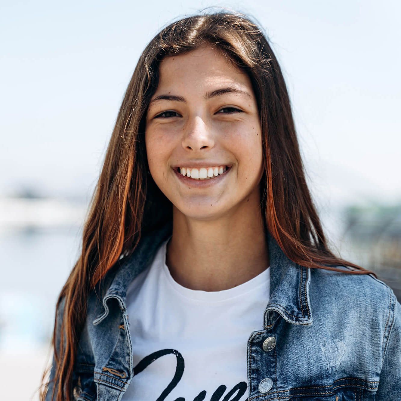 happy young woman wearing denim jacket laughing looking at camera