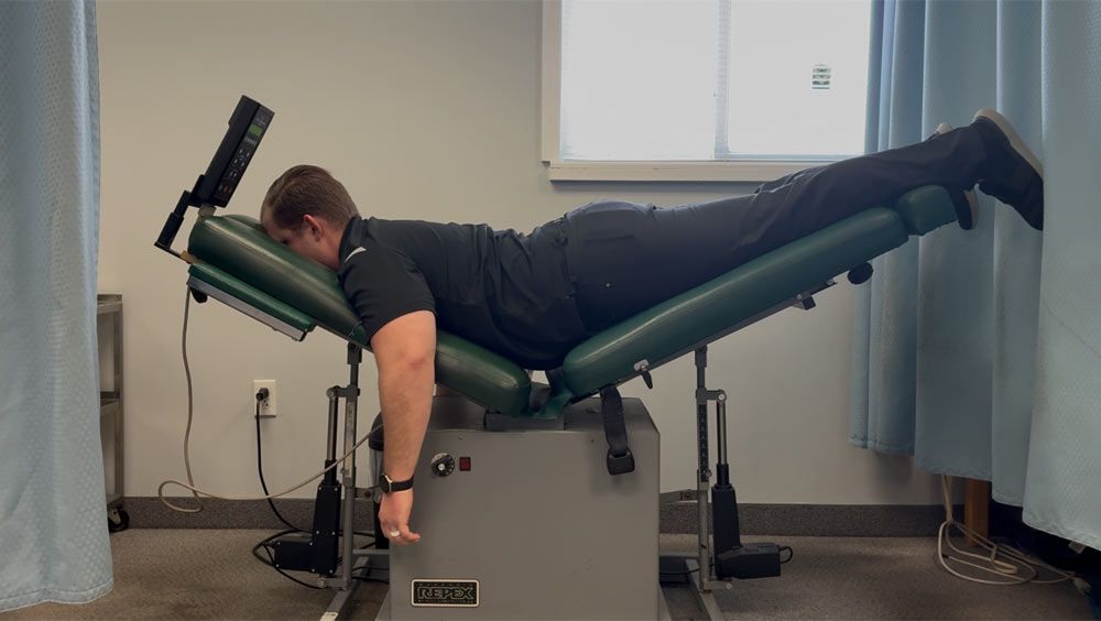 a person using a chiropractic table, likely for spinal decompression therapy.