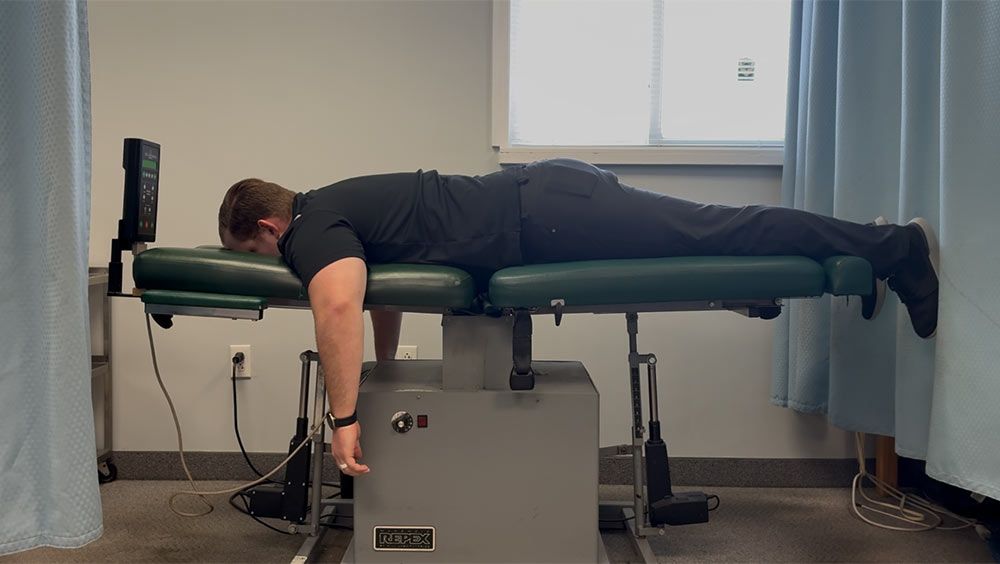 a person using a chiropractic table, likely for spinal decompression therapy.