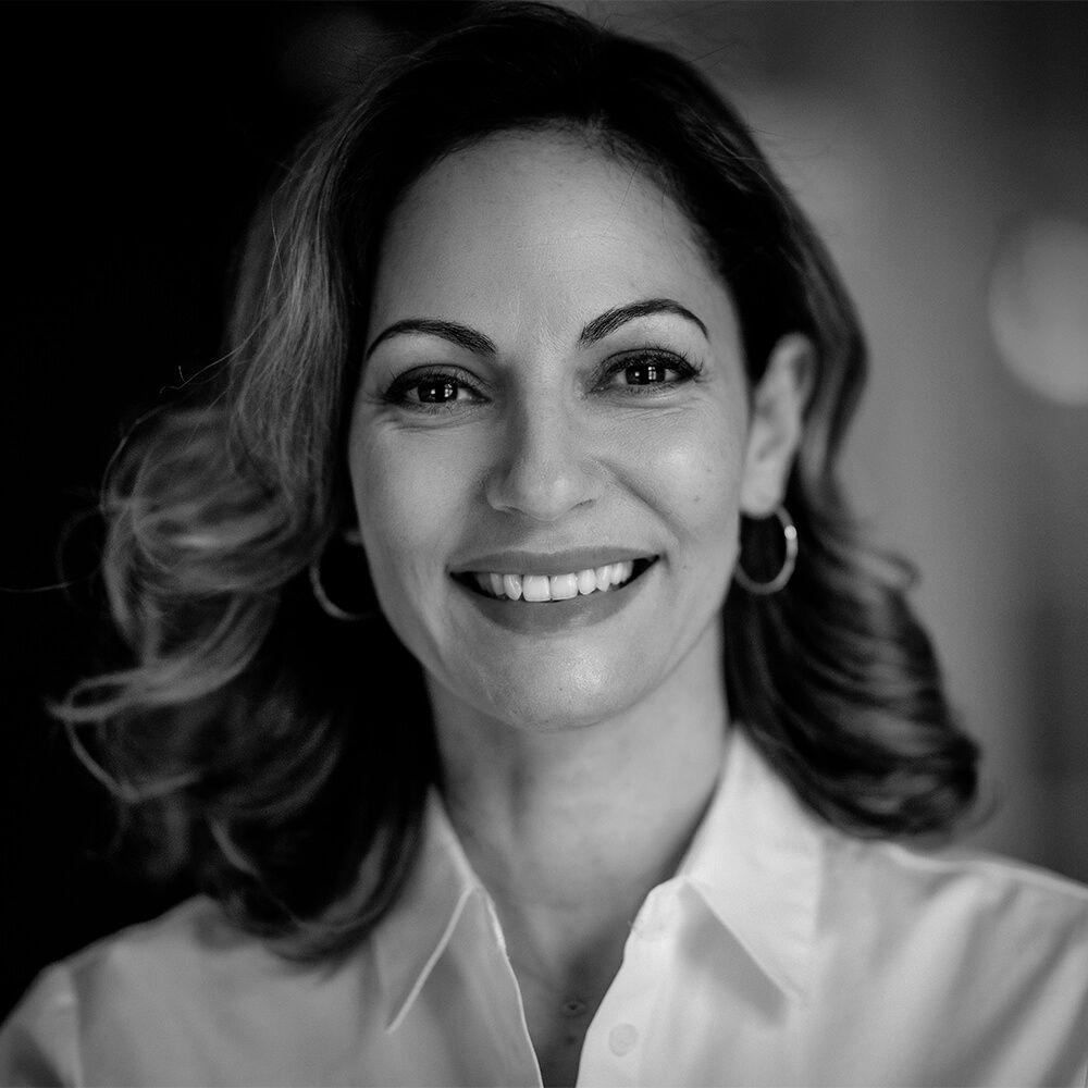 a portrait of a woman wearing a white collared shirt and hoop earrings