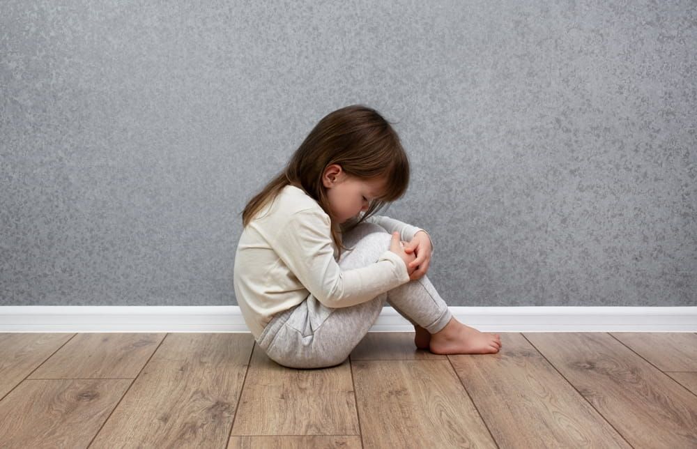 Sad and lonely child sitting alone near the wall. Domestic violence against children.