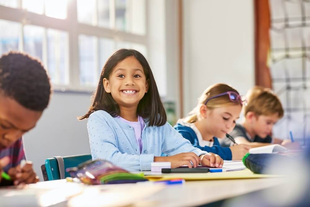 little girl is smiling in her classroom