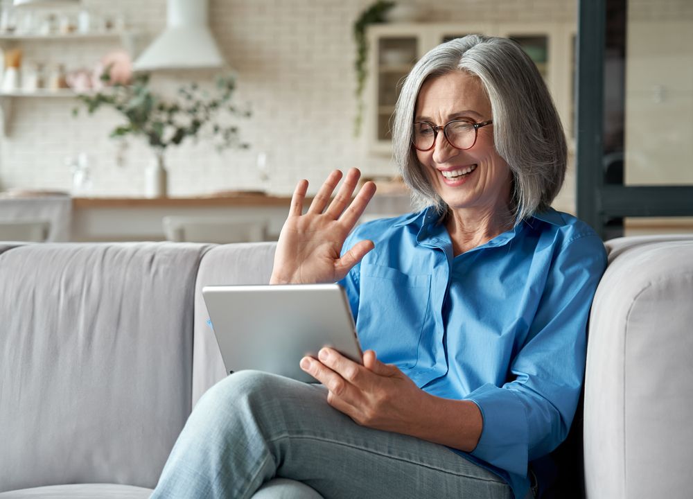 happy woman smiling at tablet as she talks to medical provicer virtually