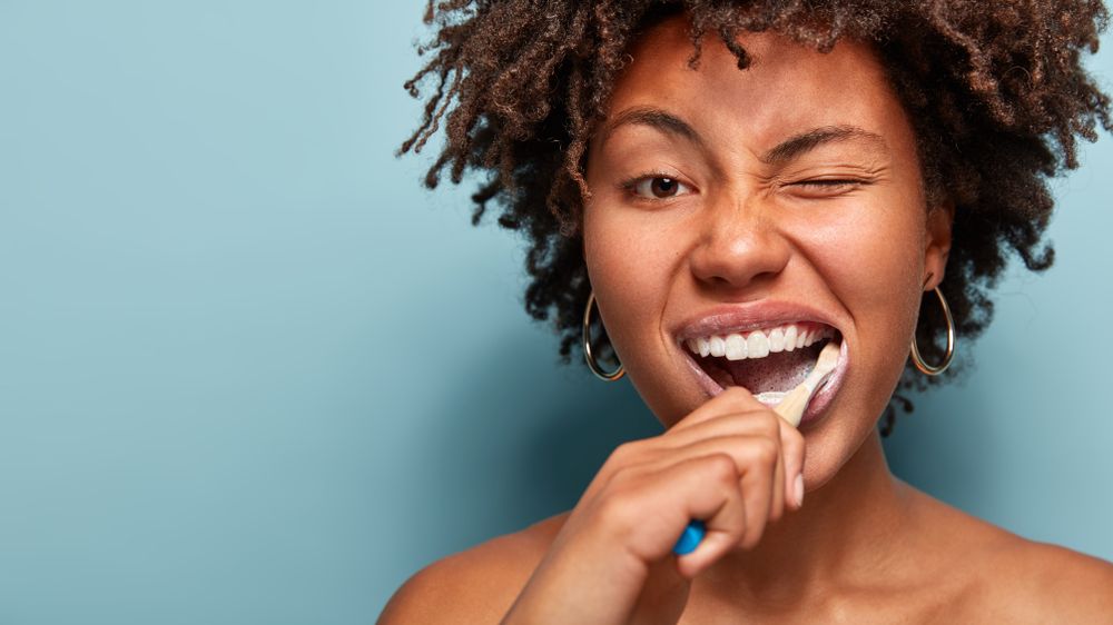 Tooth care concept. Slim naked young woman blinks eye, has daily routine after shower