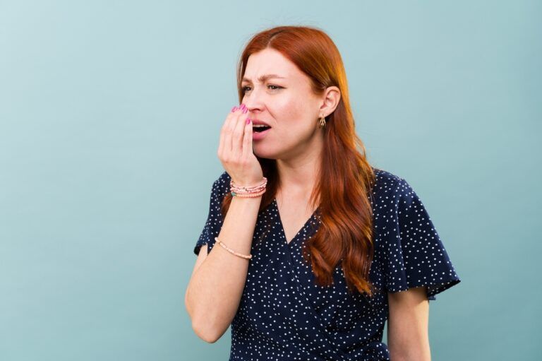 Worried caucasian redhead woman with bad breath and sick with mouth halitosis