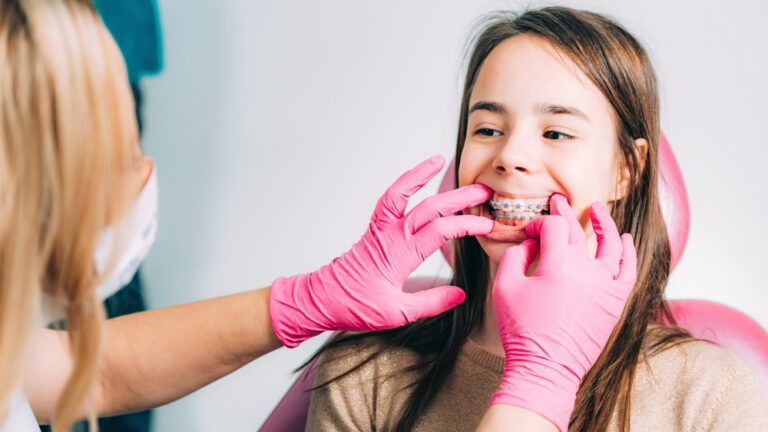Orthodontist fixing girl’s dental braces