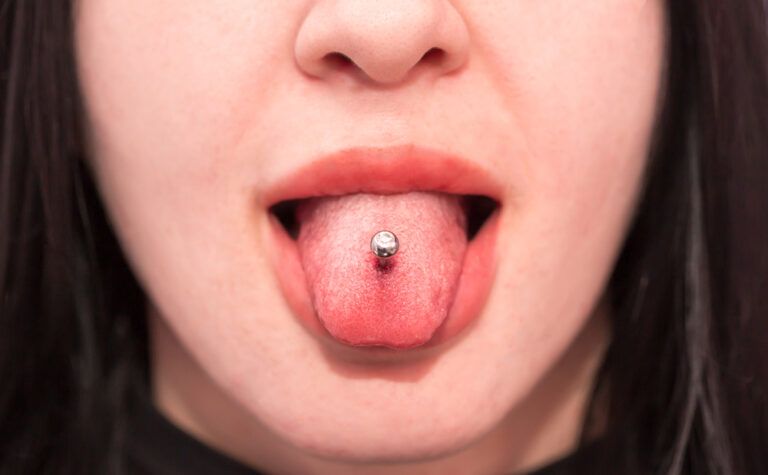 Piercing the language of the girl. Cosmetic procedure for piercing the tongue with a needle by a beautician