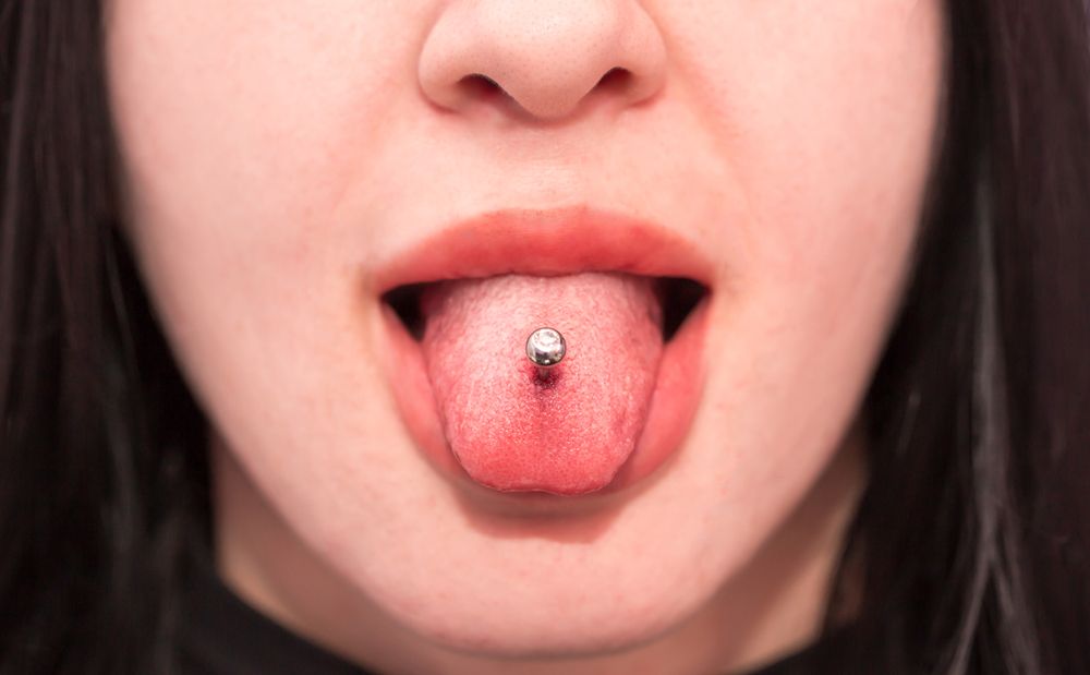 Piercing the language of the girl. Cosmetic procedure for piercing the tongue with a needle by a beautician