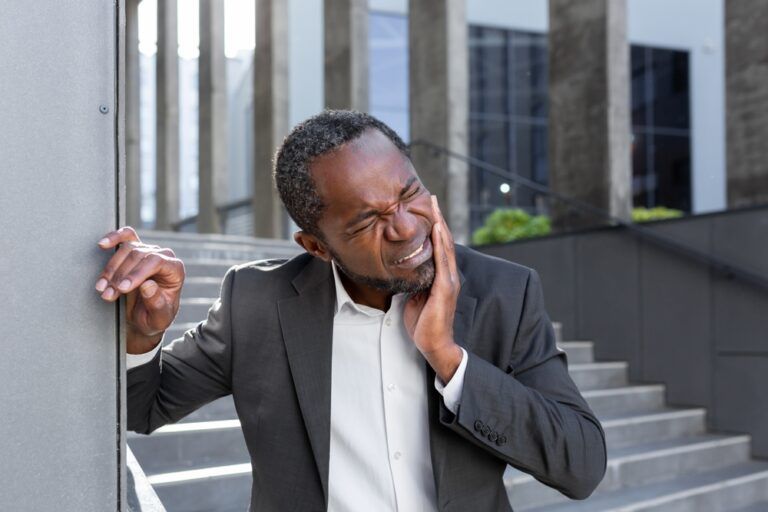 Toothache outside. An African-American man in a suit is standing near an office center