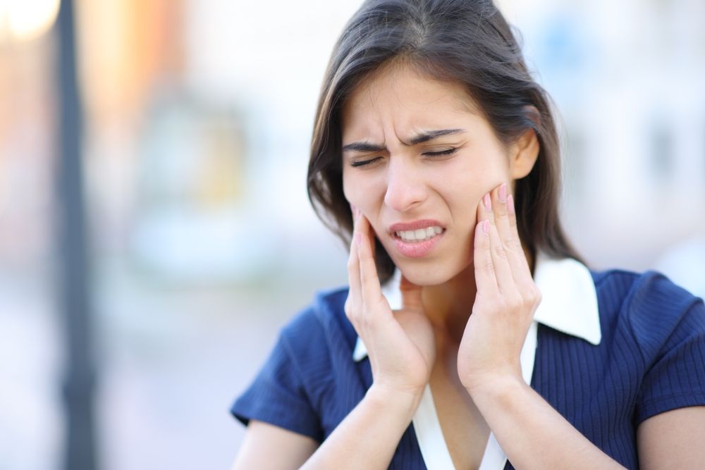Stressed woman suffering tmj disorder complaining in the stree