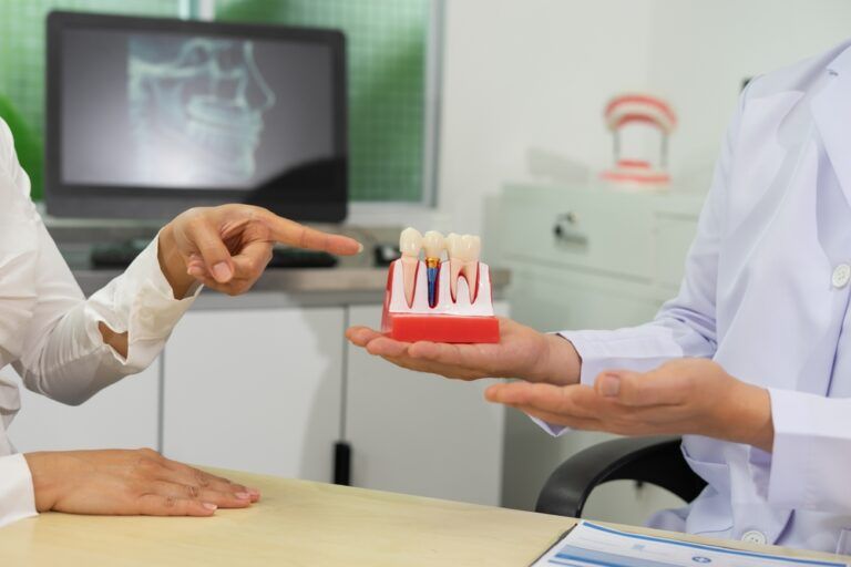 Dentist explains dental implants using model in clinic