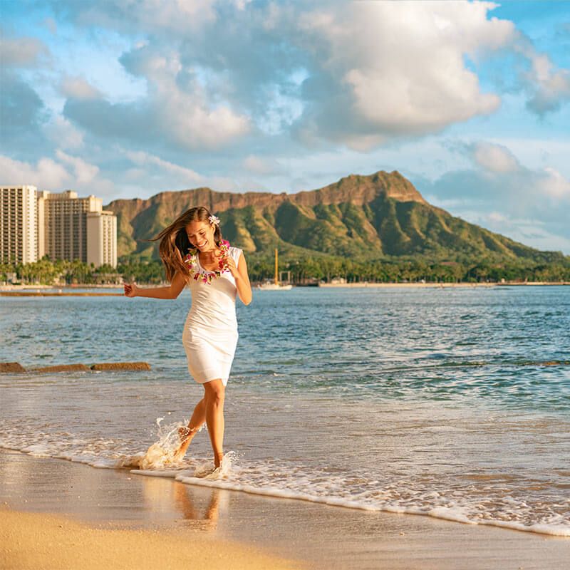 woman relaxing on Waikiki beach running carefree enjoying holidays