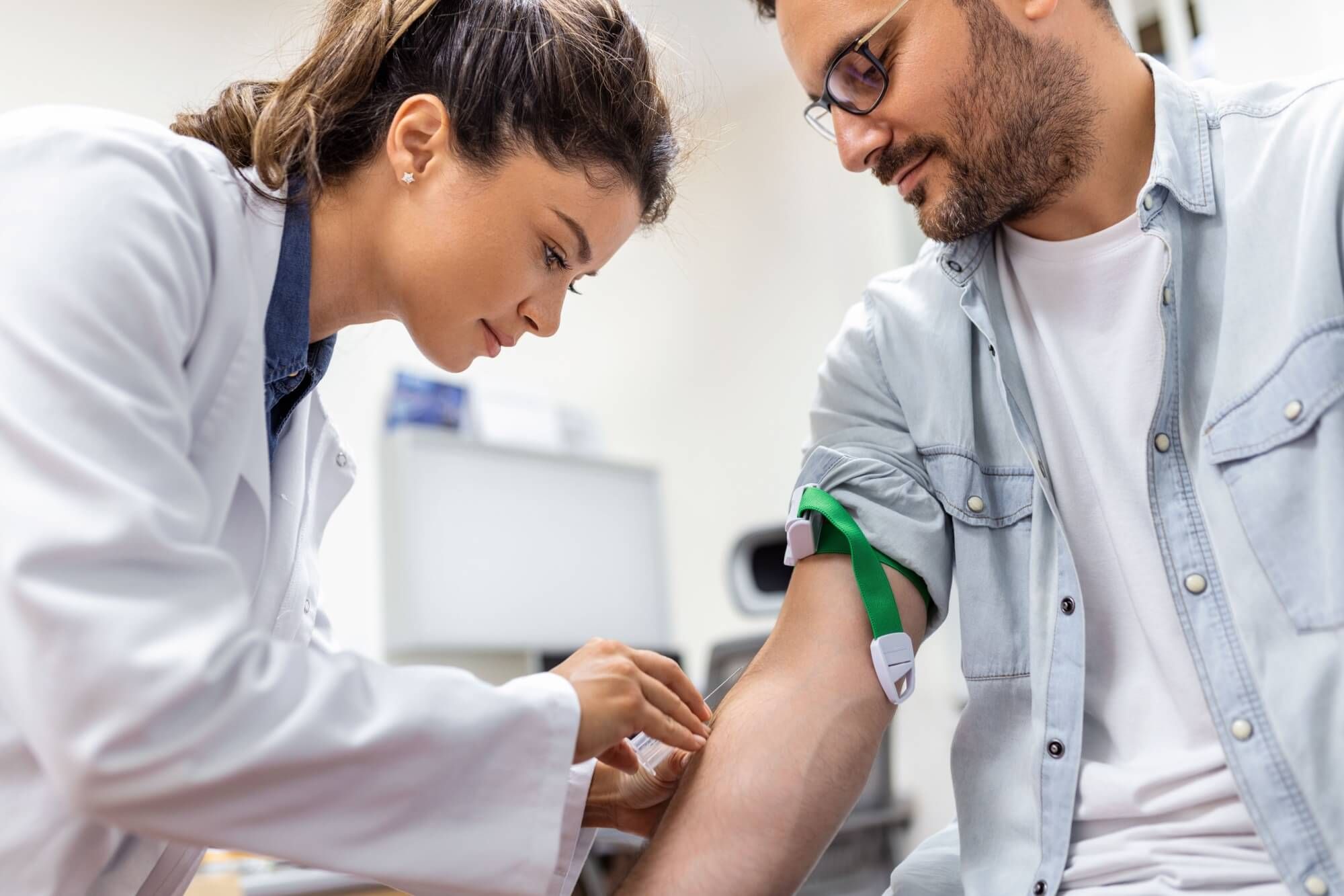 Friendly hospital phlebotomist collecting blood sample from patient in lab