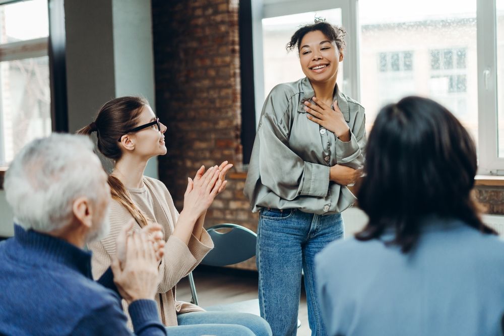 Diverse group of people sitting in chairs, clapping and celebrating