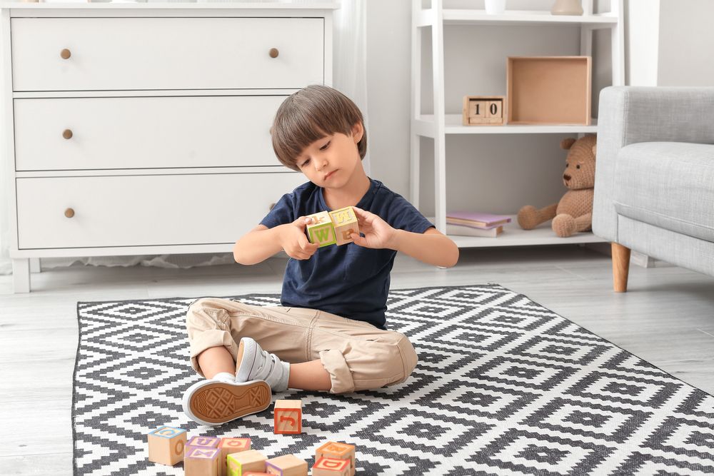 Little boy with autistic disorder playing with cubes at home