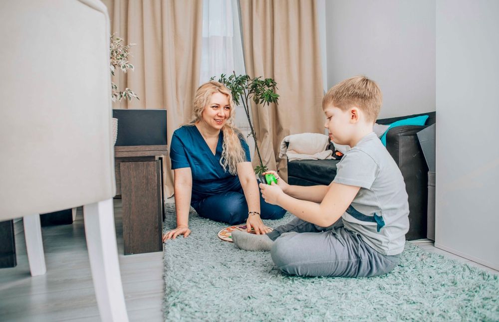 Child participating in a therapy session with a professional using a hands-on learning approach, focusing on social and cognitive development