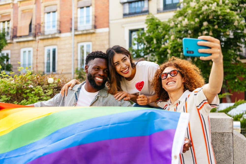 Happy friends taking selfie at pride parade celebrating lgbtqia plus rights