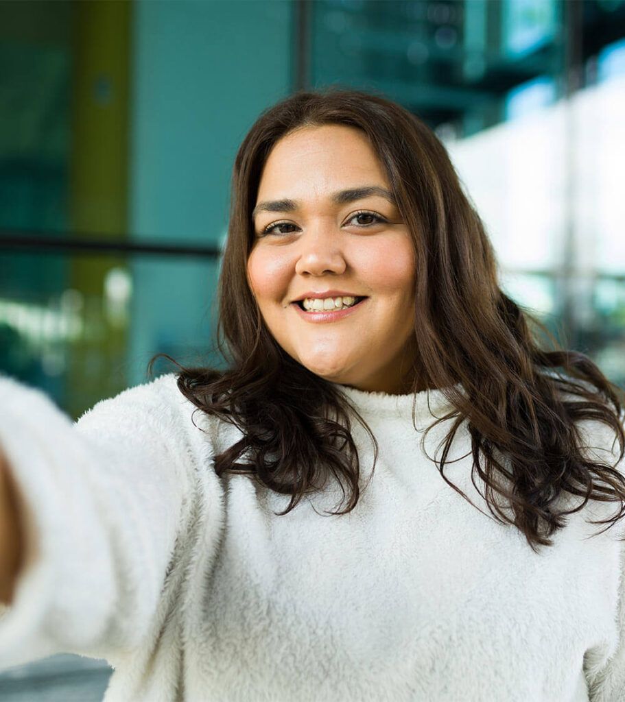 Personal perspective of a latin beautiful fat woman smiling while making eye contact taking a selfie in the city