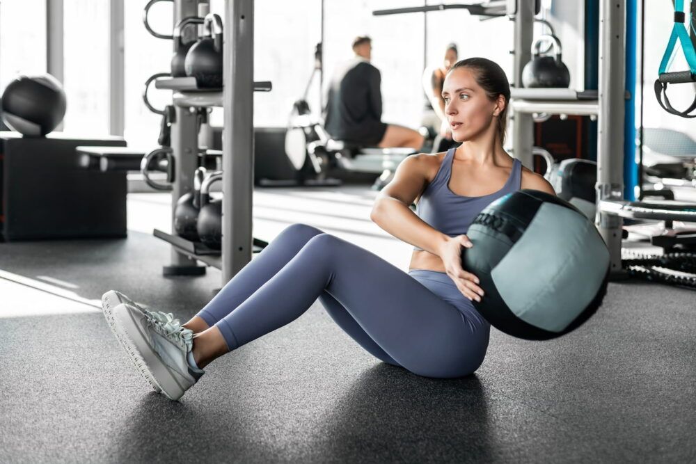 Fit and muscular woman exercising with medicine ball at gym